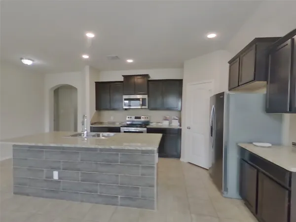 a kitchen with kitchen island granite countertop a stove and a refrigerator