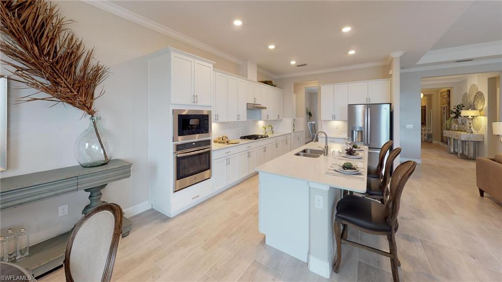 20259 Kingmont Drive Estero, FL 33928 - Photo 5 of 14 a kitchen with stainless steel appliances kitchen island granite countertop a table chairs microwave and sink