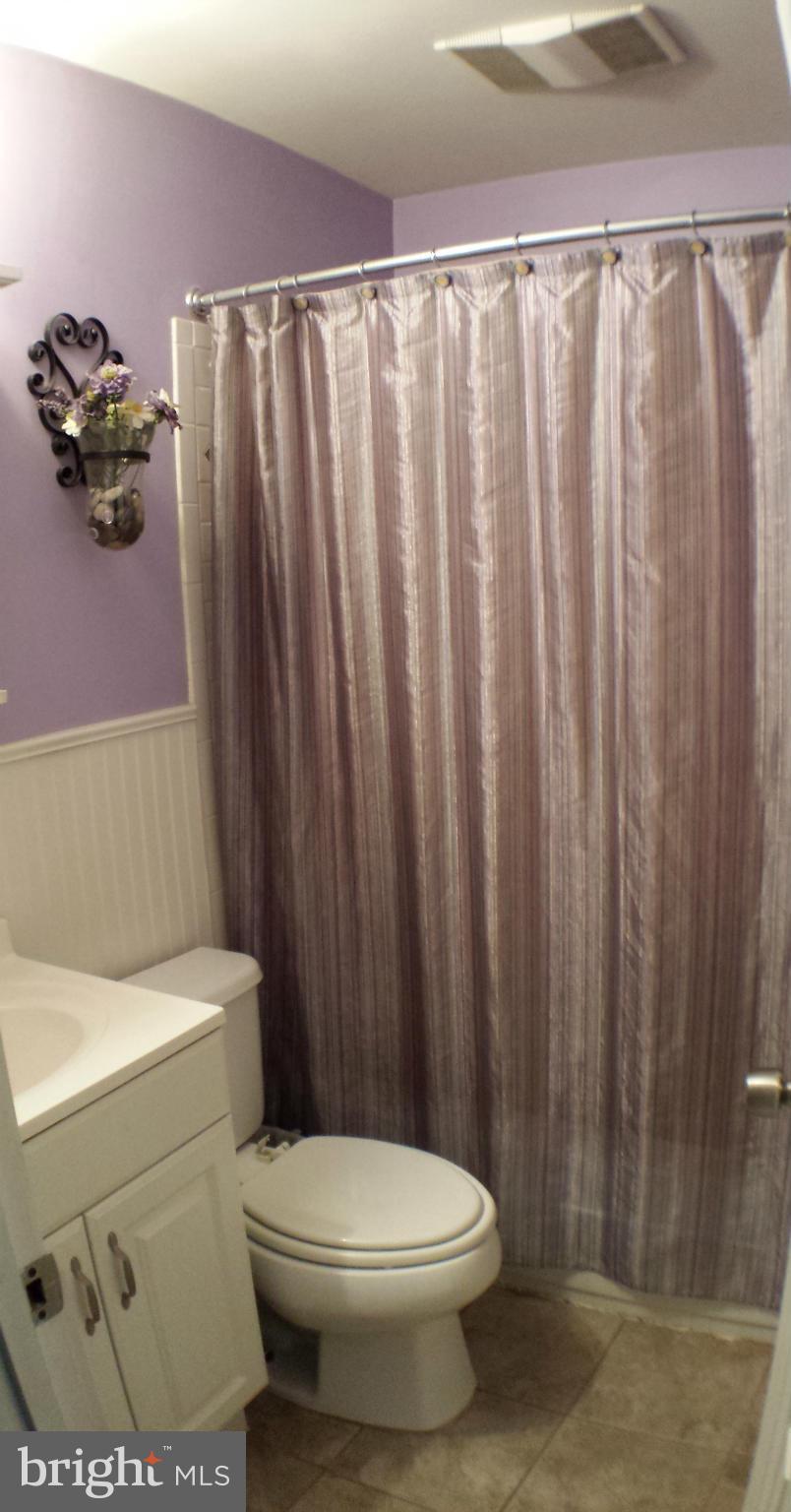 913 Elm Road Baltimore, MD 21227 - Photo 19 of 28 a white toilet sitting next to a shower curtain