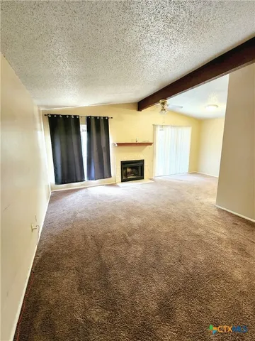 view of an empty room with a fireplace and a window