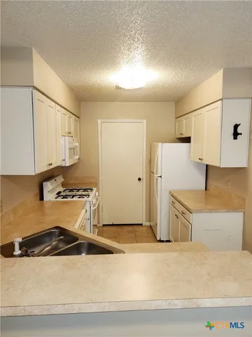 a kitchen with stainless steel appliances granite countertop a refrigerator a stove and white cabinets