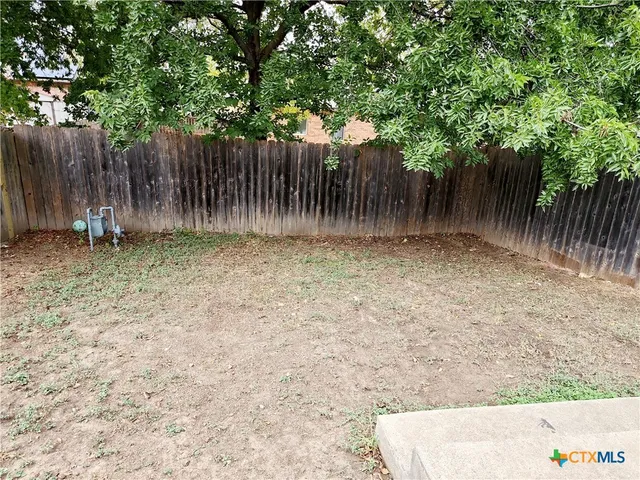 a backyard of a house with lawn chairs and wooden fence