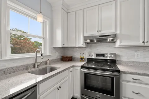 a kitchen with stainless steel appliances granite countertop white cabinets and a stove top oven