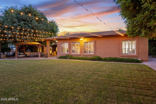 a view of a patio with table and chairs under an umbrella with large trees