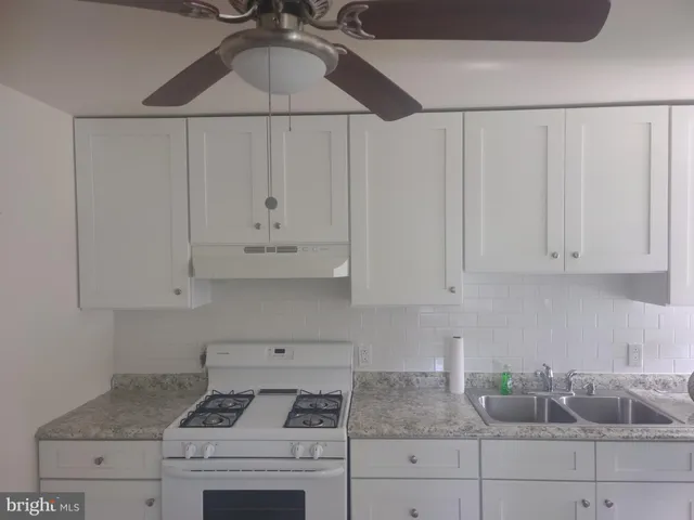 a kitchen with granite countertop white cabinets and white appliances