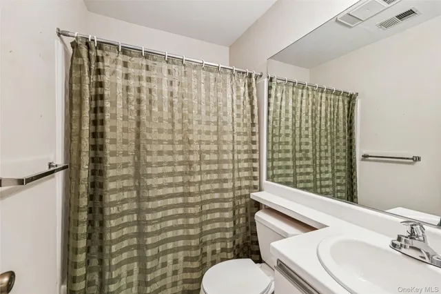 a bathroom with a sink a toilet and shower curtain