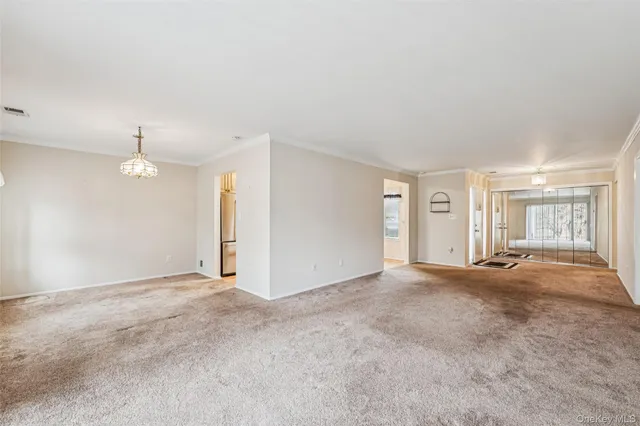 a view of an empty room with kitchen and window