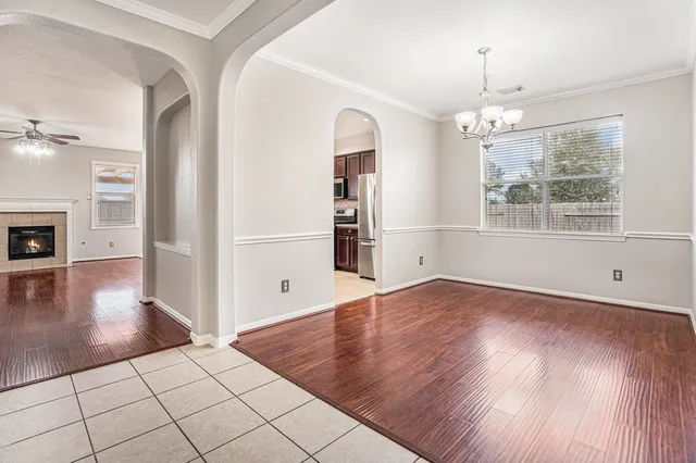 an empty room with wooden floor chandelier and glass door
