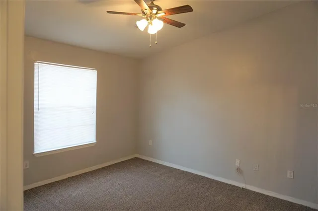 an empty room with a window and a fan
