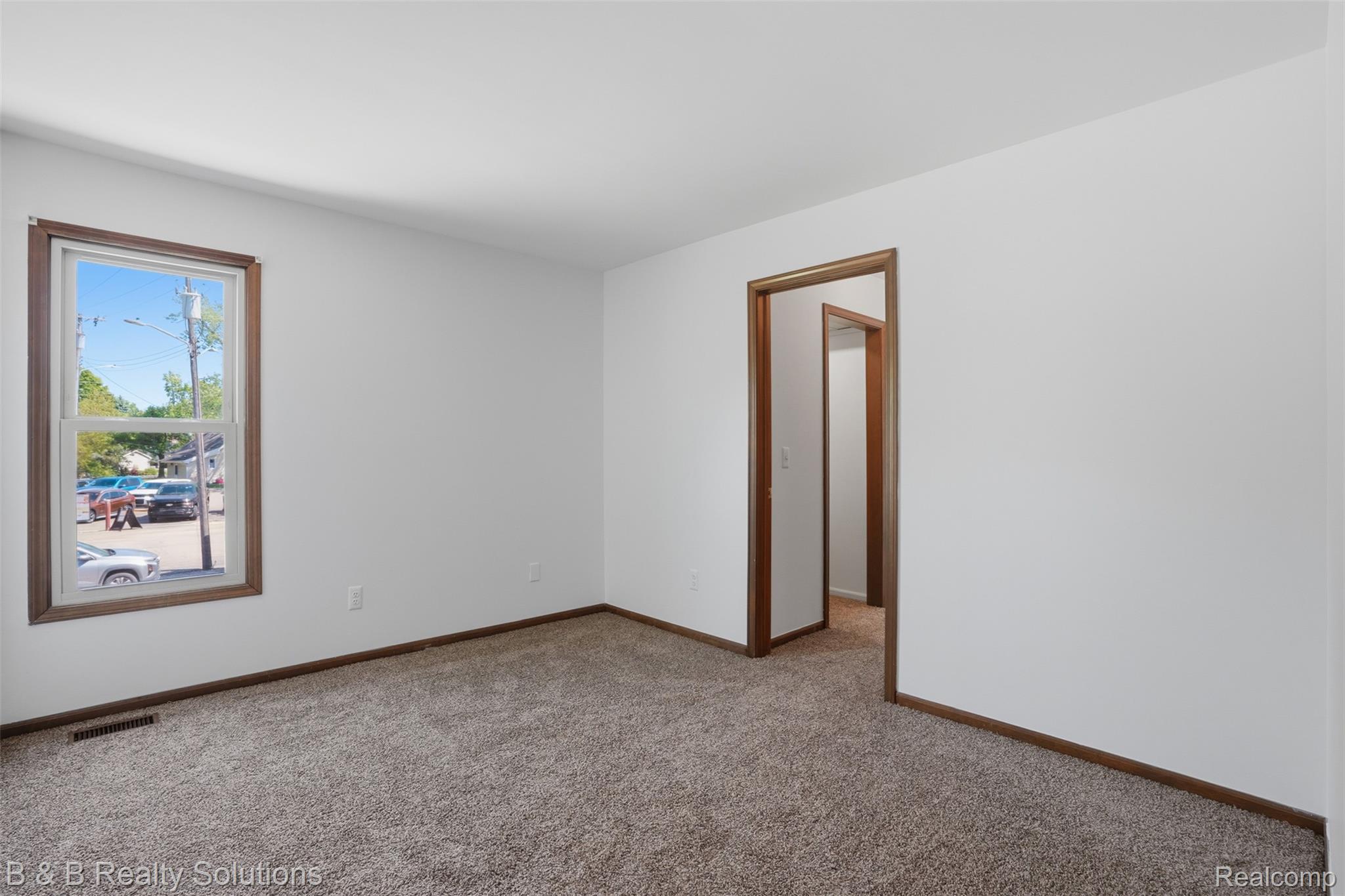 780 North Van Dyke Road, Unit APARTMENT #1 Almont, MI 48003 - Photo 23 of 28 Bright interior space featuring neutral wall paint, light-colored carpet flooring, and classic wood-finish trim around windows and doorways