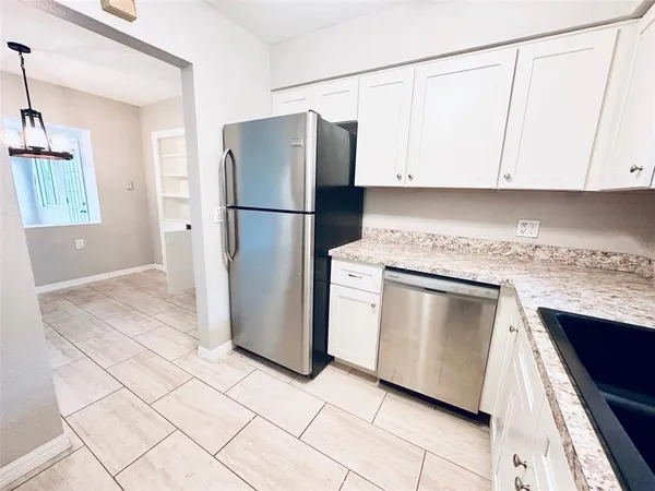 a kitchen with granite countertop white cabinets and refrigerator