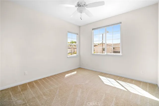 an empty room with windows and fan