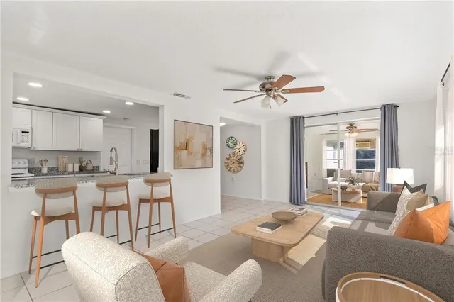 a living room with furniture kitchen view and a large window