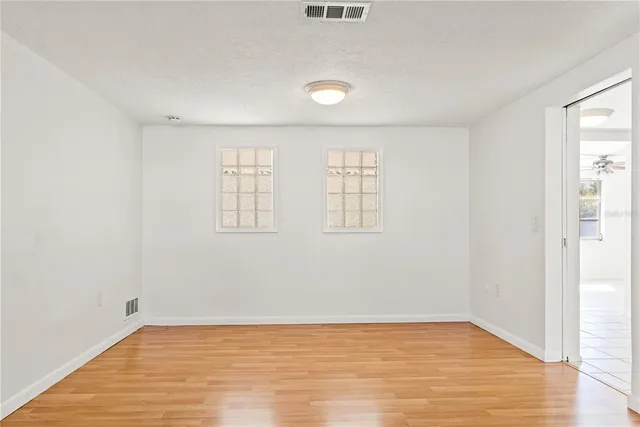 an empty room with wooden floor and windows