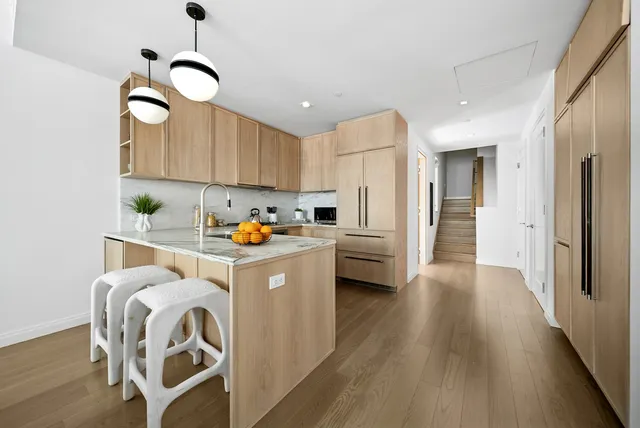 a kitchen with a refrigerator a sink dishwasher and white cabinets with wooden floor