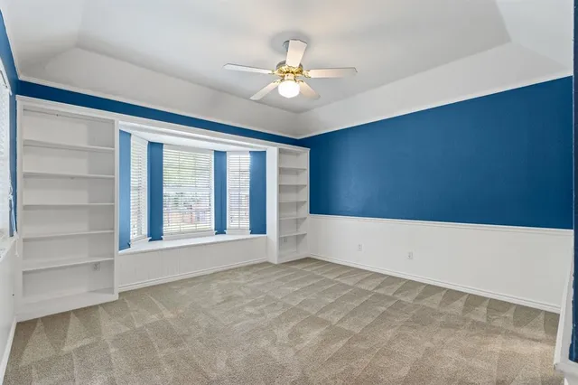 a view of an empty room with chandelier fan and fire place