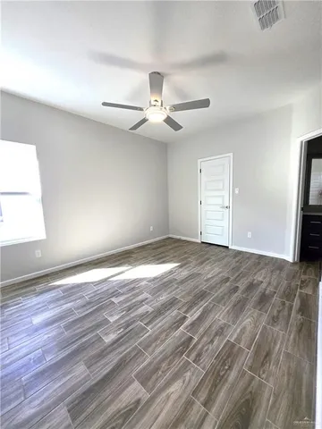 an empty room with wooden floor ceiling fan and windows
