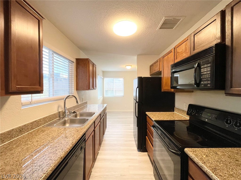 1834 North Decatur Boulevard, Unit 204 Las Vegas, NV 89108 - Photo 4 of 17 A galley kitchen with abundant natural light features warm wood cabinetry and durable speckled counters.