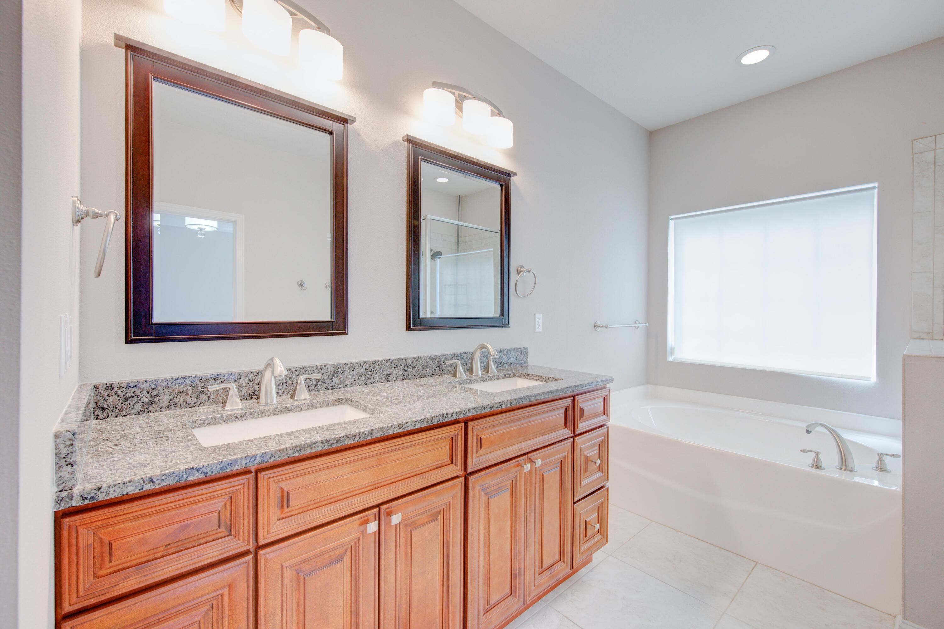 4557 Hermosa Road Crestview, FL 32539 - Photo 19 of 29 a bathroom with a granite countertop double vanity sink and mirror with bathtub