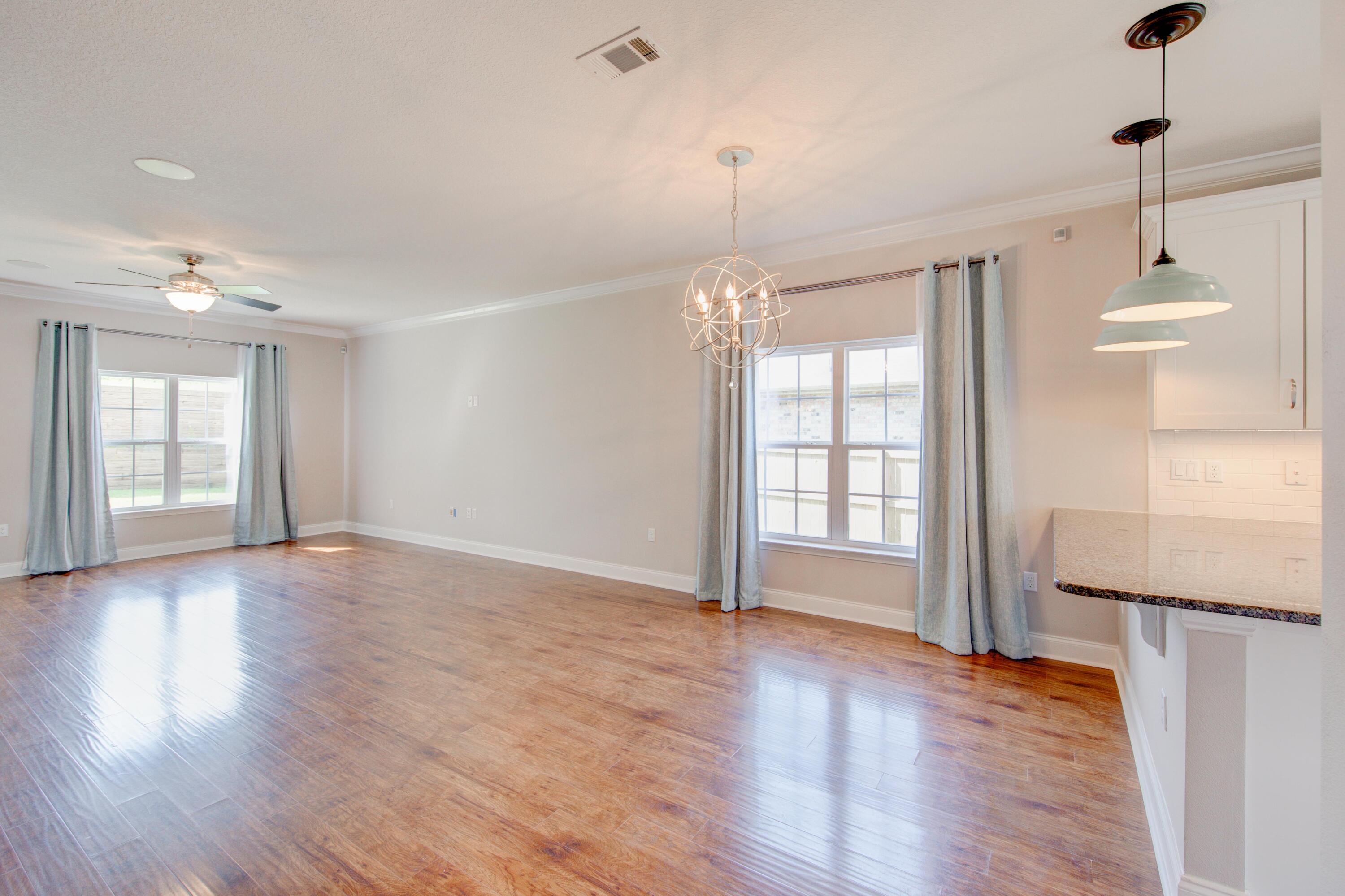 4557 Hermosa Road Crestview, FL 32539 - Photo 8 of 29 a view of an empty room with wooden floor and a window