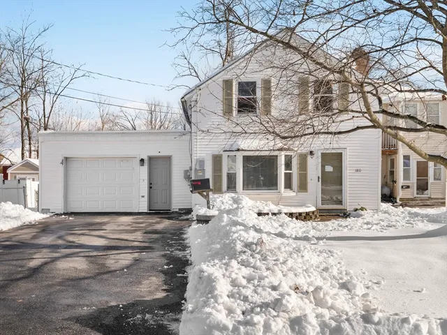 a view of a white house next to a yard with large trees