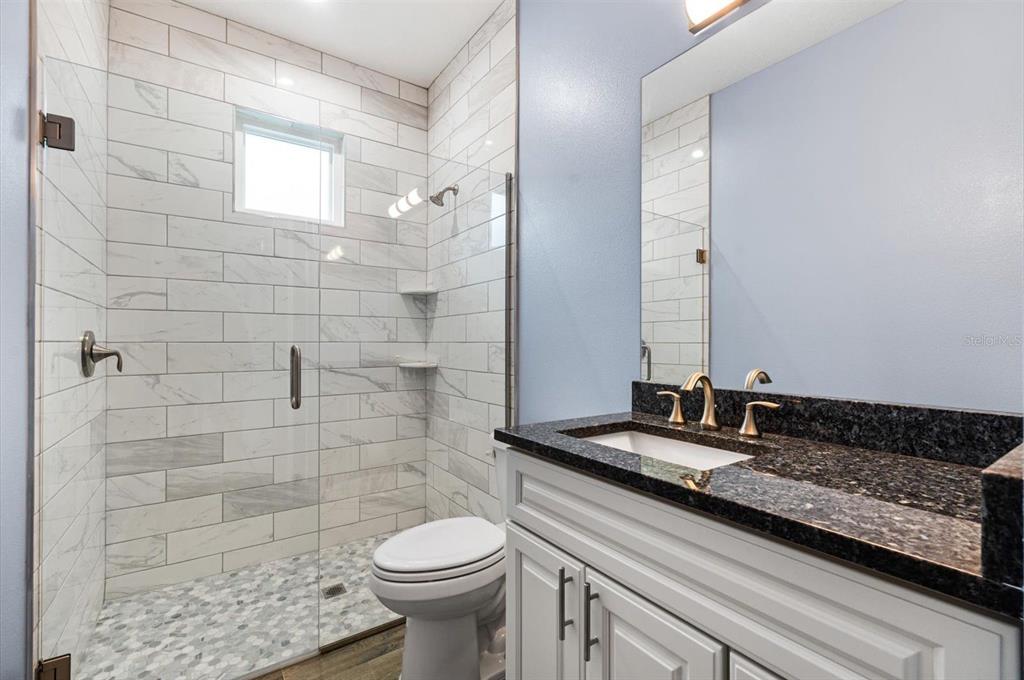 4 Uturn Court Palm Coast, FL 32164 - Photo 21 of 26 a bathroom with a granite countertop sink a toilet and a mirror