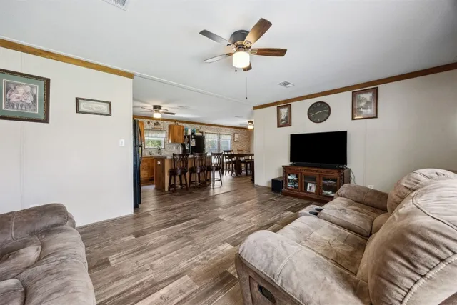 a kitchen with stainless steel appliances granite countertop a stove top oven a refrigerator a dining table and chairs with wooden floor