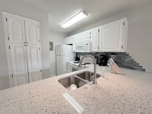 a kitchen with white cabinets and white appliances