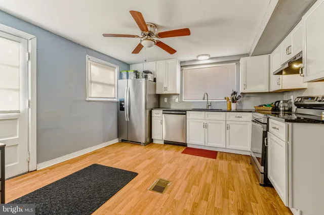 a kitchen with stainless steel appliances a sink cabinets and wooden floor