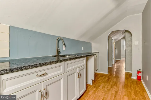 a hallway with granite countertop a sink and wooden floor