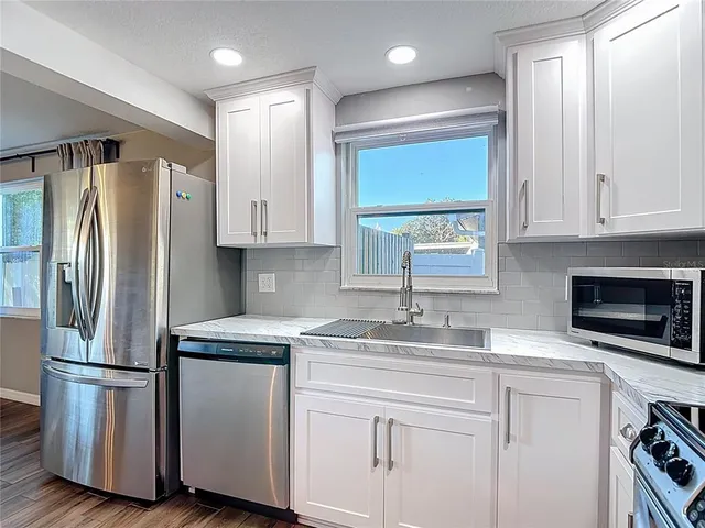 a kitchen with white cabinets and appliances
