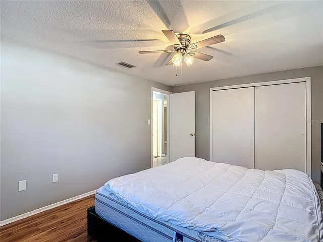 a view of empty room with wooden floor and fan