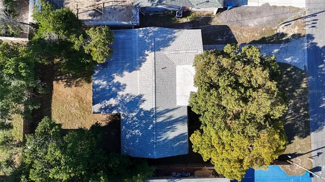 an aerial view of a house with swimming pool and large trees