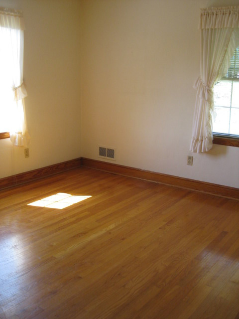 4656 Elva Road Northwest Roanoke, VA 24017 - Photo 8 of 10 an empty room with wooden floor and windows with curtains