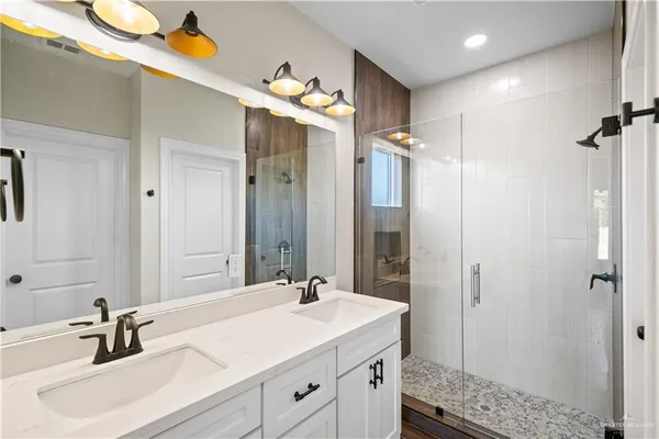 a bathroom with a sink vanity granite shower and a mirror