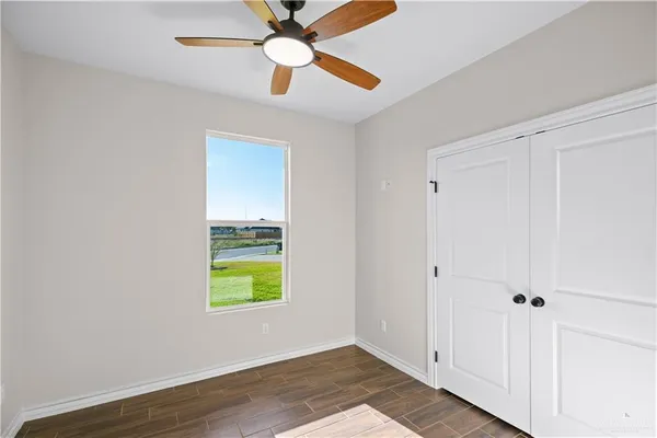 a view of an empty room with window and wooden floor