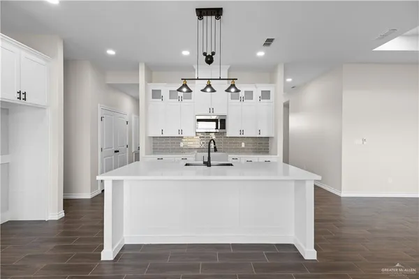 a large white kitchen with a large island oven a stove and white cabinets with wooden floor