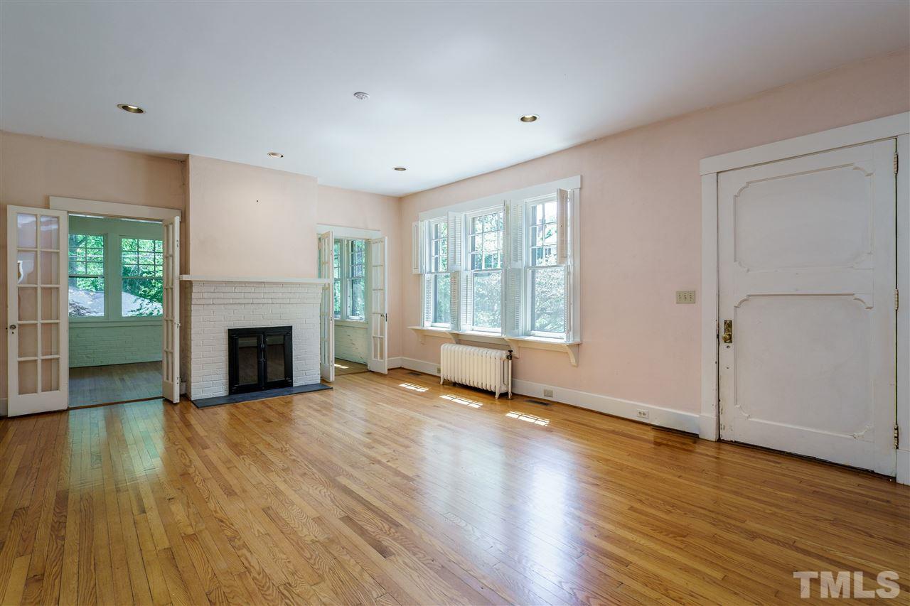 311 Hillcrest Road Raleigh, NC 27605 - Photo 4 of 30 an empty room with wooden floor fireplace and windows