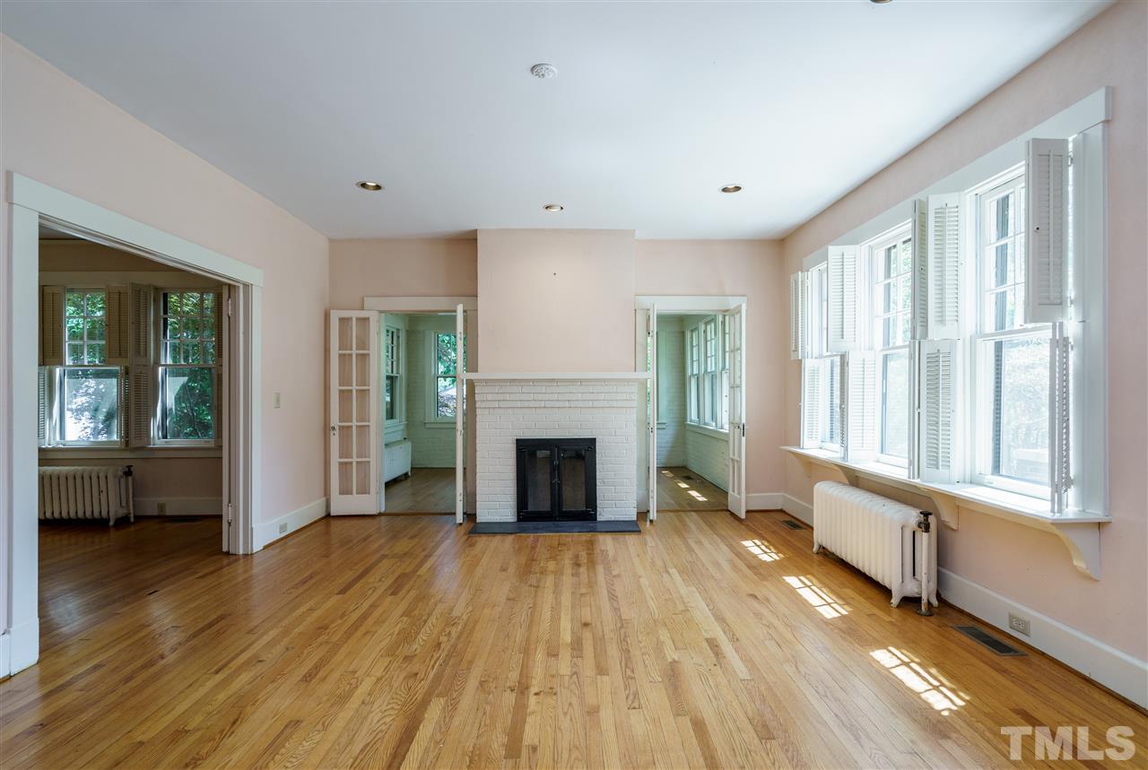 311 Hillcrest Road Raleigh, NC 27605 - Photo 5 of 30 a view of a livingroom with wooden floor a fireplace and windows
