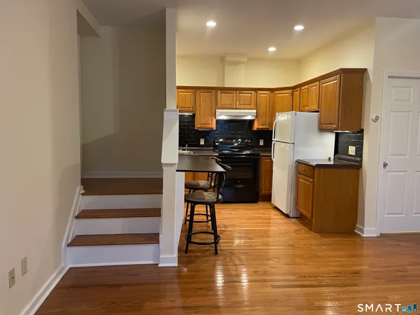a kitchen with stainless steel appliances a refrigerator and wooden floor