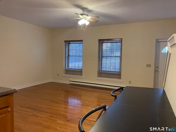 a view of an empty room with window and wooden floor