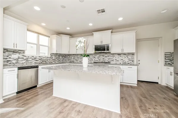 a kitchen with stainless steel appliances kitchen island granite countertop a stove a sink and white cabinets