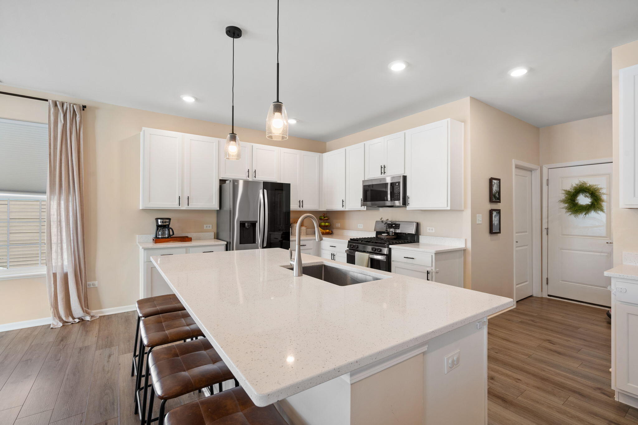 11664 Thomas Street Winfield, IN 46307 - Photo 11 of 30 a kitchen with stainless steel appliances kitchen island granite countertop a refrigerator a stove top oven a sink dishwasher and white cabinets with wooden floor