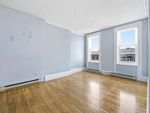 a view of an empty room with window and wooden floor