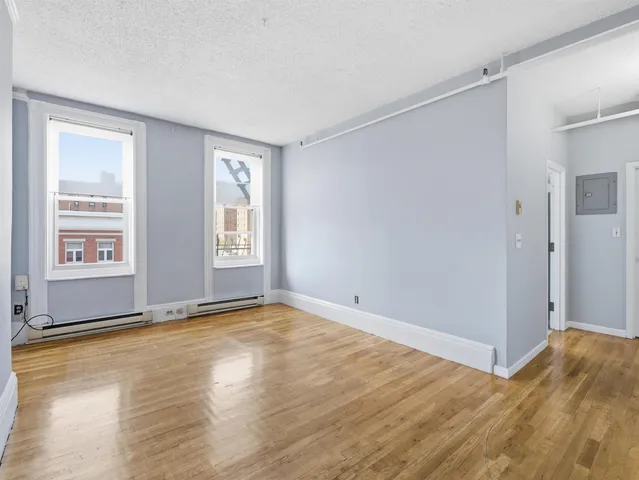 a view of an empty room with window and wooden floor
