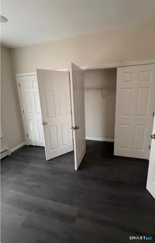 a view of an empty room with wooden floor and closet