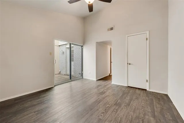 a view of an empty room with window and wooden floor