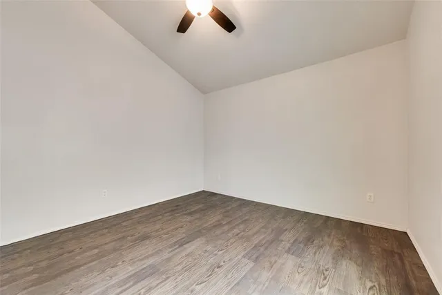 an empty room with wooden floor ceiling fan and window