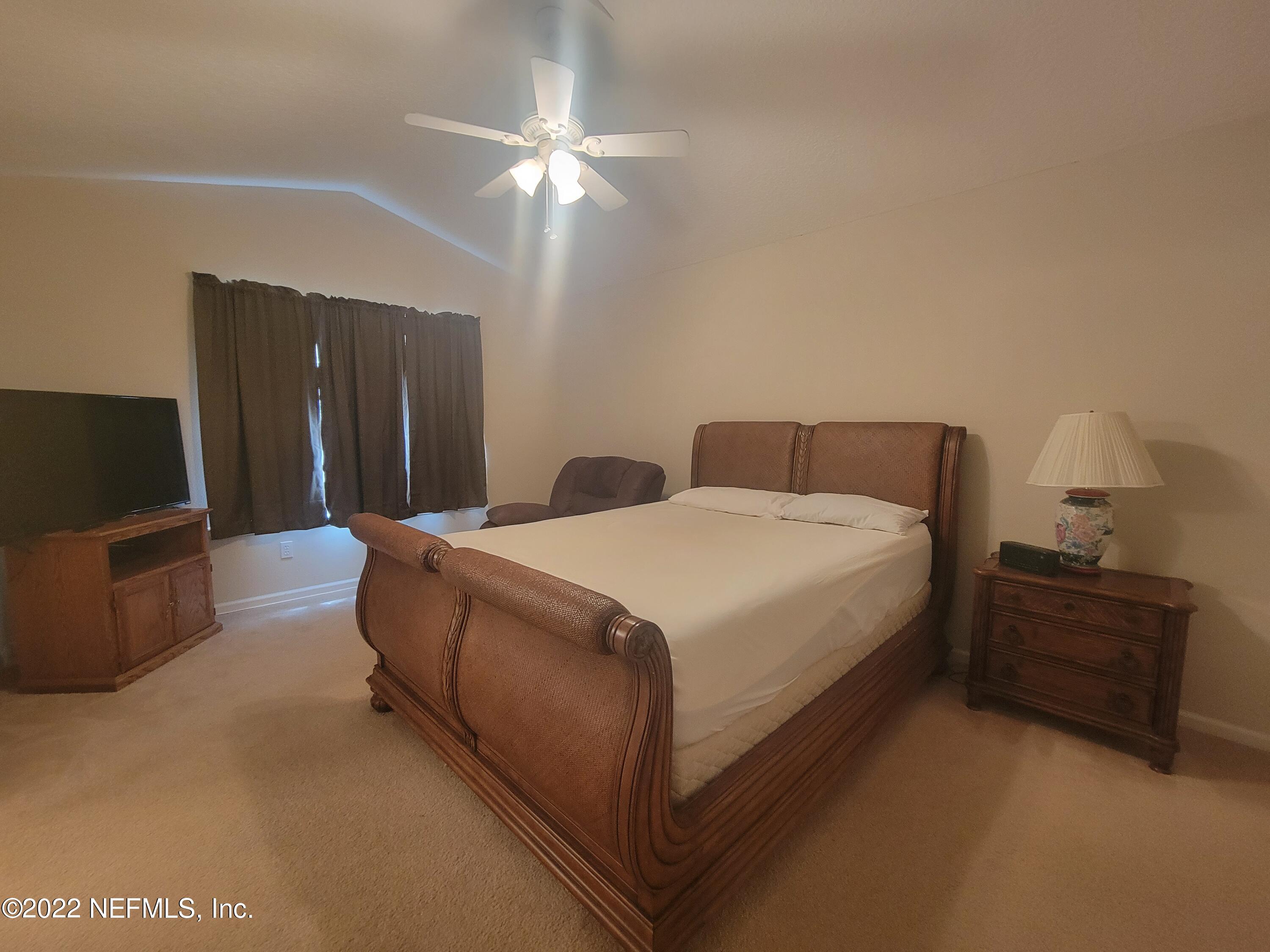 5260 Collins Road, Unit 605 Jacksonville, FL 32244 - Photo 7 of 13 a spacious bedroom with a bed and a chandelier