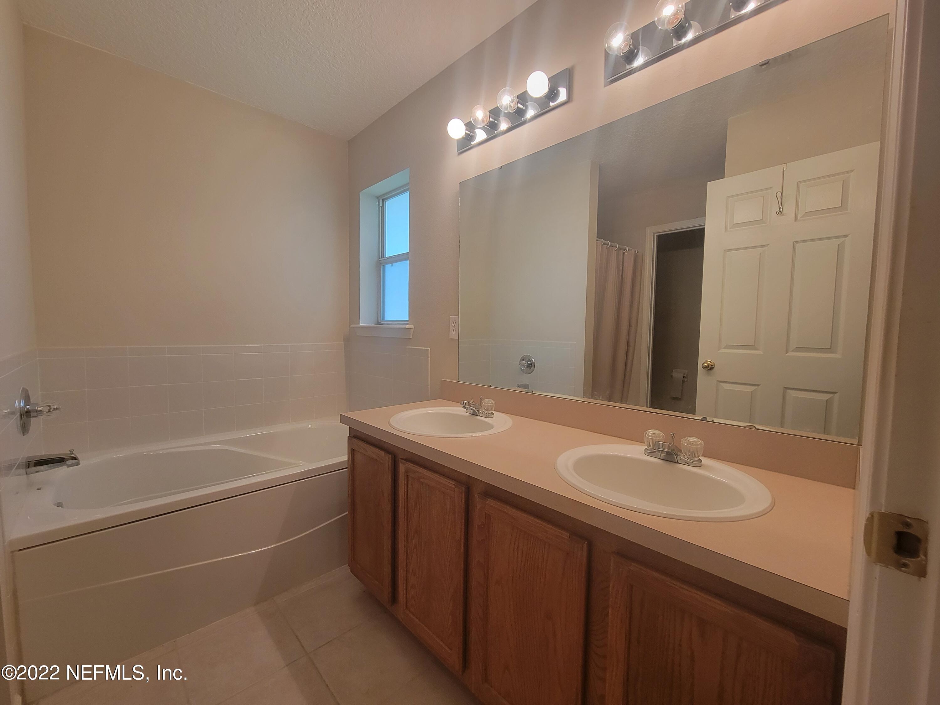 5260 Collins Road, Unit 605 Jacksonville, FL 32244 - Photo 8 of 13 a bathroom with a sink double vanity granite tub shower and a mirror